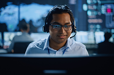 Portrait of Professional IT Technical Support Specialist Working on Computer in Monitoring Control Room with Digital Screens.