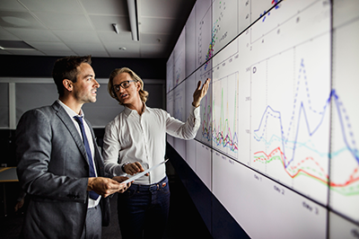 Two men looking at a lightboard with data analytics