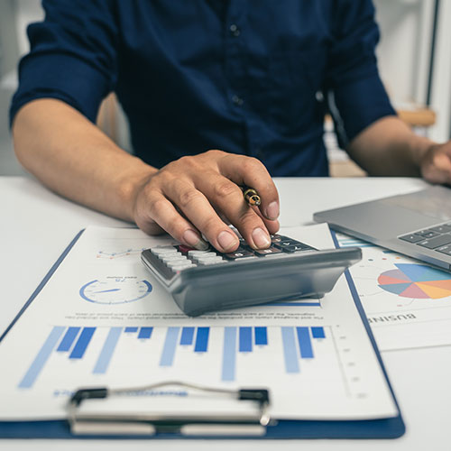 Person using a calculator, spreadsheets on the desktop