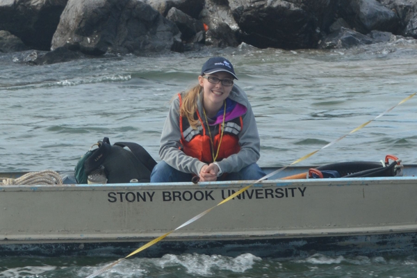 Kaitlin sits on a small boat in Flax Pond