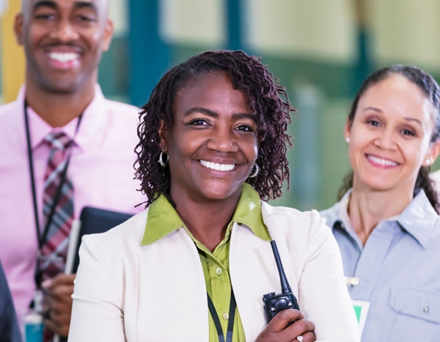 An ethnically diverse group of teachers -- four women and one man -- standing in a school hallway.