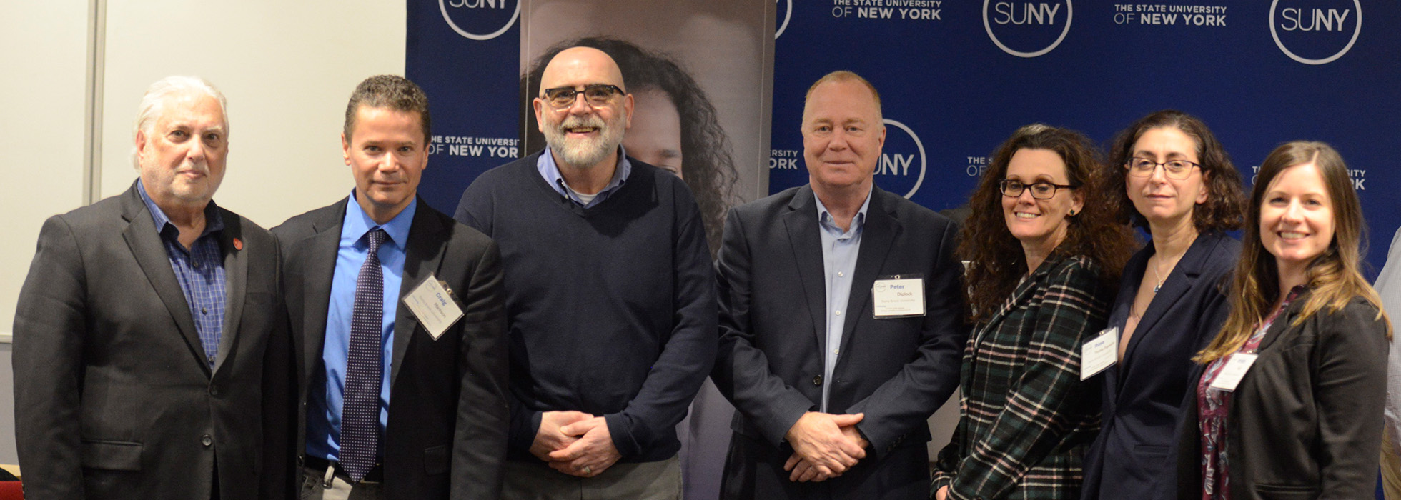 Stony Brook faculty and staff in front of a SUNY Online backdrop