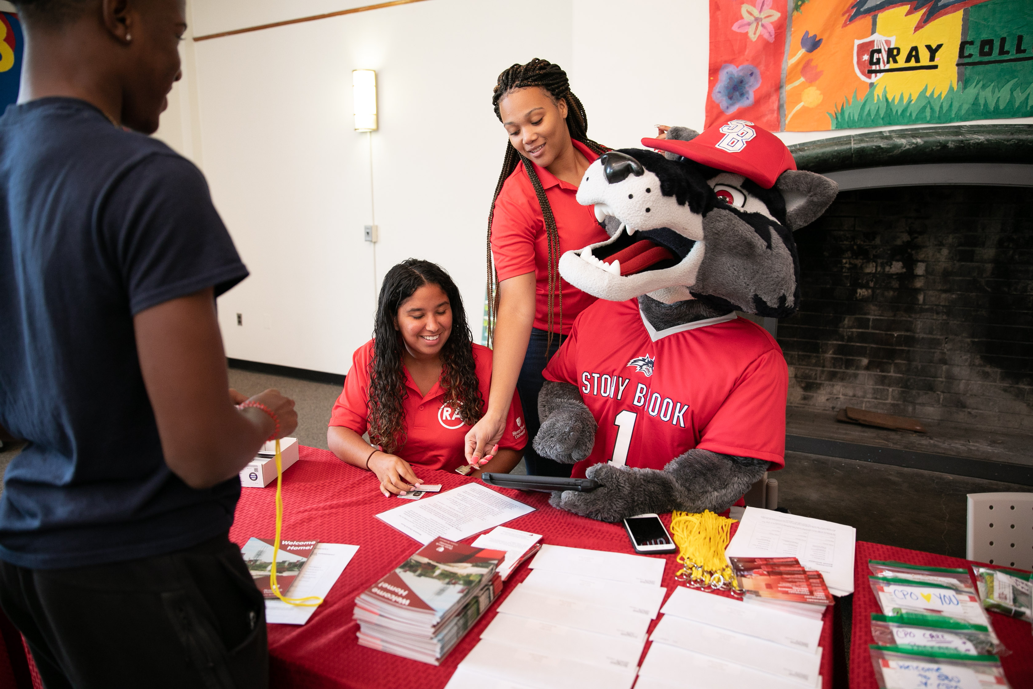 Wolfie sitting with two staff members. Wolfie is looking at and holding an IPad.